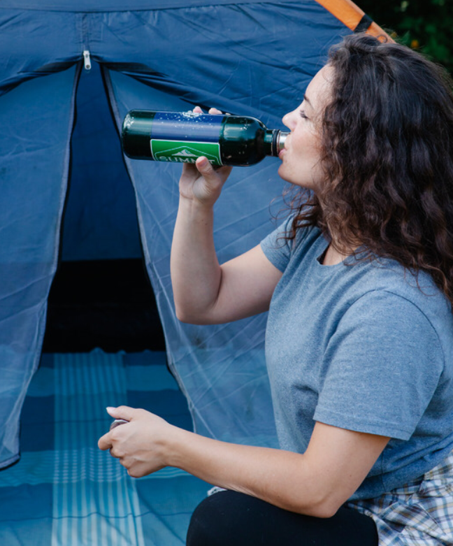 Woman by tent drinking water